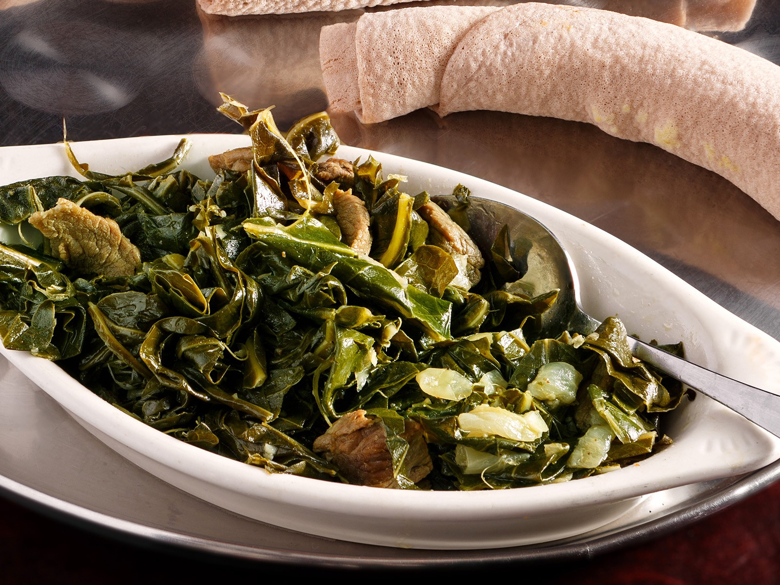 Collard greens slow-cooked in spiced butter with onions, garlic, ginger, and turmeric. A staple of Ethiopian cuisine served alongside injera. Simple ingredients, extraordinary depth of flavor.