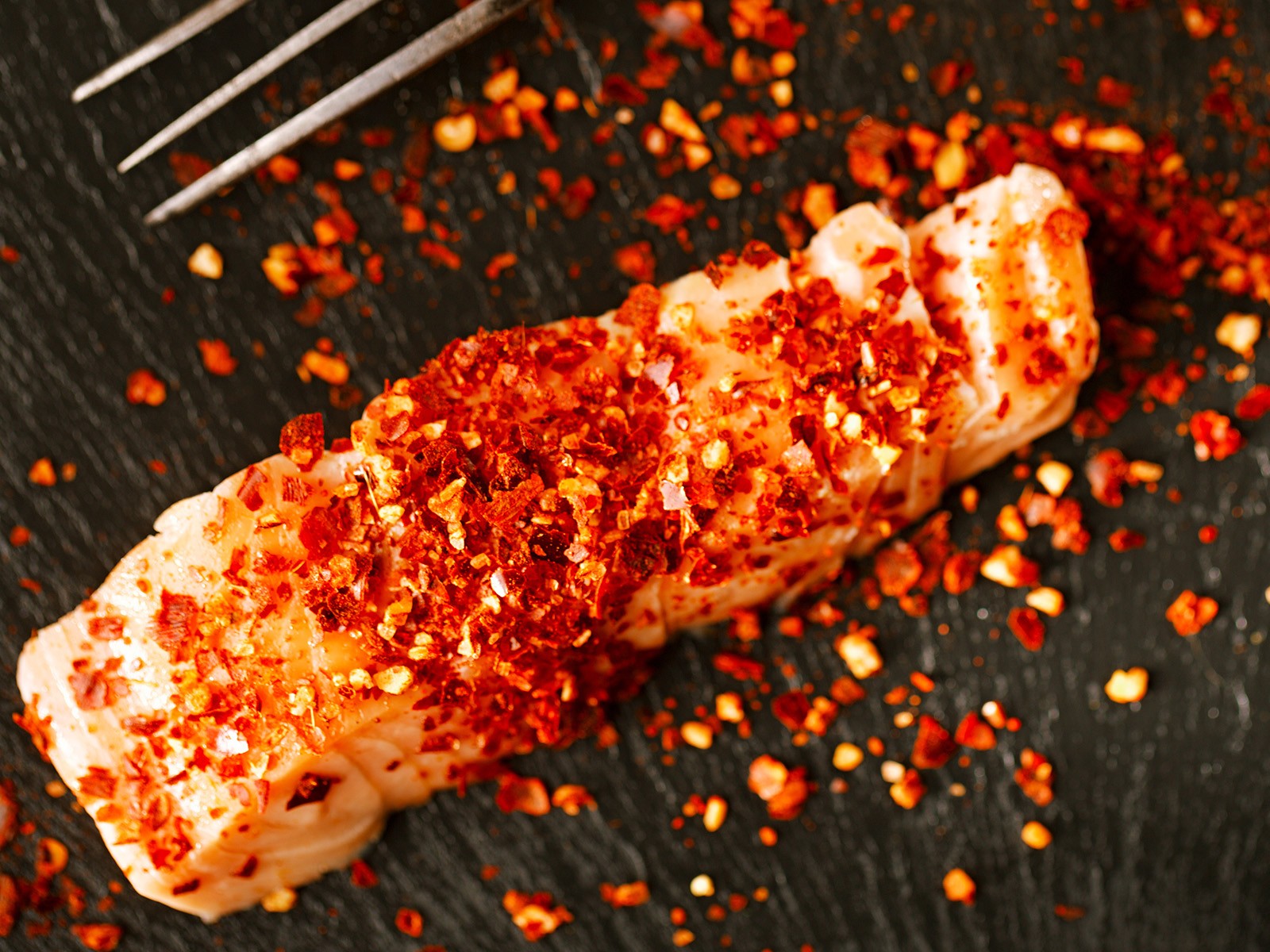 Salmon fillet coated in homemade harissa — roasted red peppers, chiles, garlic, cumin, and coriander — and roasted until caramelized. Served over herbed couscous with preserved lemon yogurt.