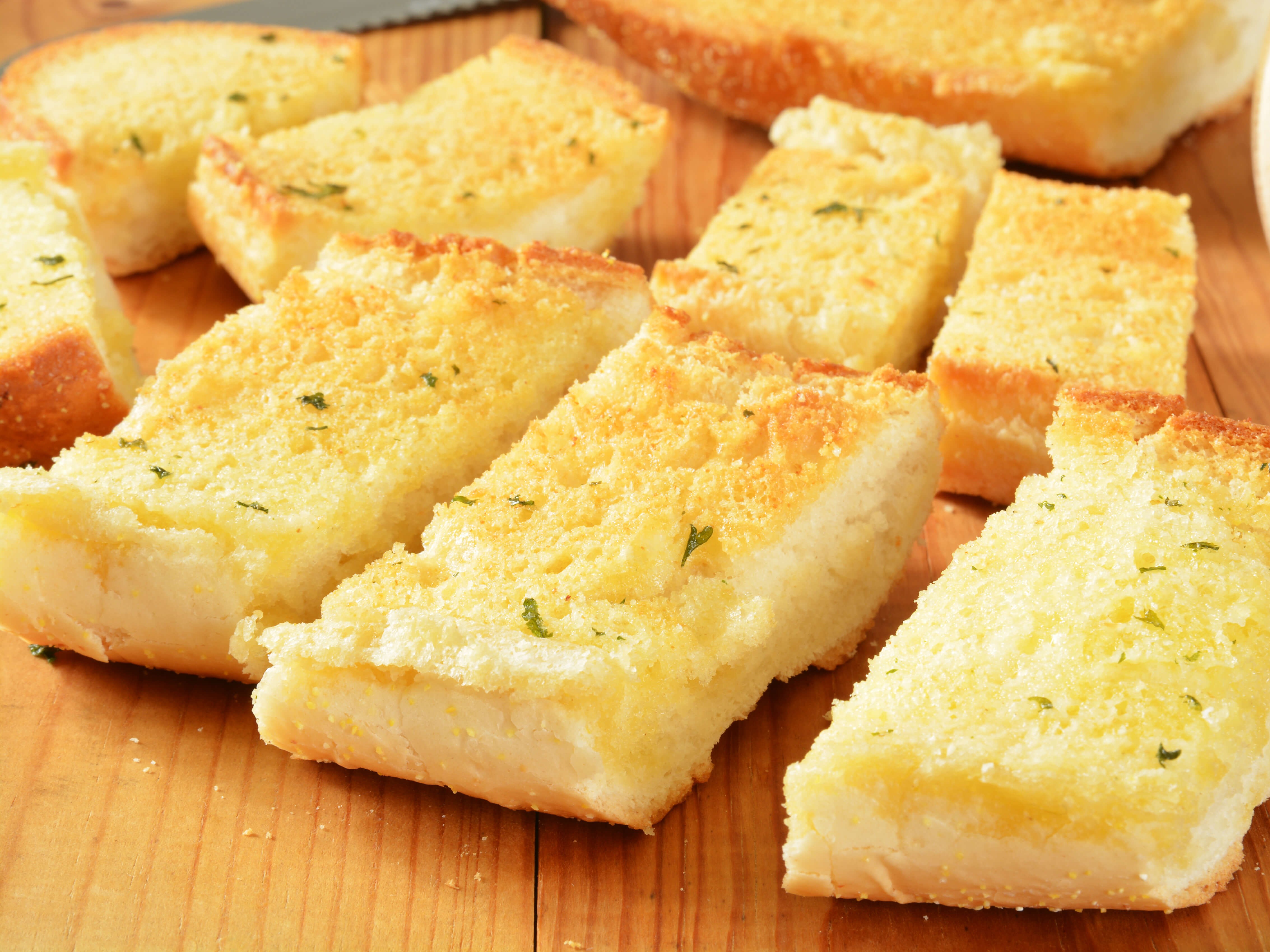 A whole baguette split and spread with compound butter — softened butter, roasted garlic, fresh parsley, parmesan, and a touch of lemon. Broiled until the edges char and the center is melted.