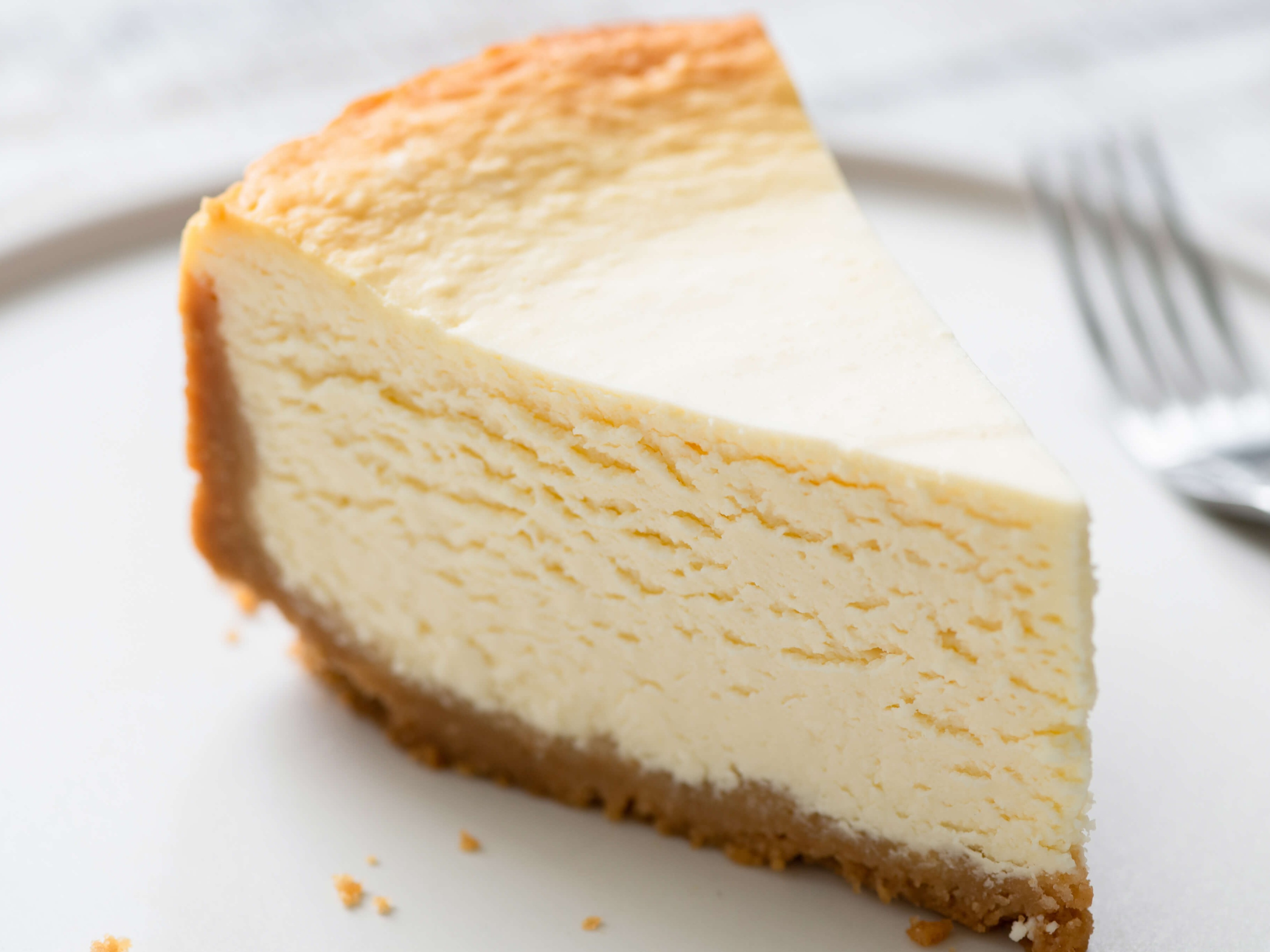 Dense, creamy, and slightly tangy New York cheesecake with a graham cracker crust. Baked in a water bath for an even texture. No cracks. The sour cream topping adds a layer of tang that makes it pop.