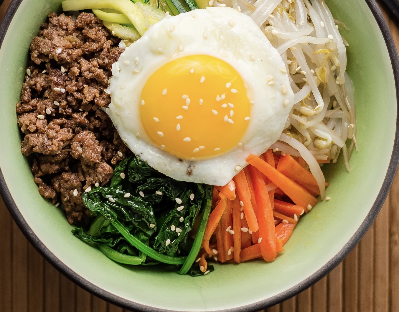 A colorful rice bowl topped with sautéed veggies, protein, and a spicy gochujang sauce. The ultimate customizable Korean comfort meal.